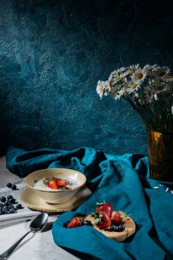 Chia tohum ve masa örtüsü ve çiçekler ile tabloda olgun yaz meyveleri ile kase