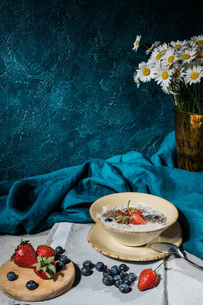 Chia seeds pudding in bowl with strawberries and blueberries on table