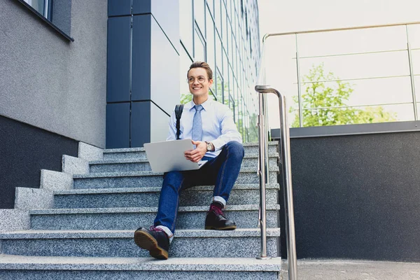 Bonito Sorrindo Jovem Freelancer Óculos Sentado Escadas Usando Laptop — Fotografia de Stock