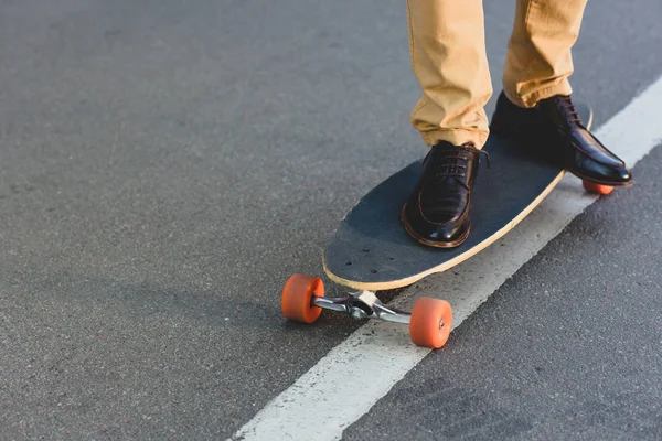 cropped shot of young man standing on skateboard on street