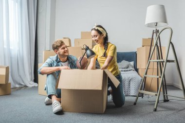 interracial young couple unpacking boxes while moving into new home clipart