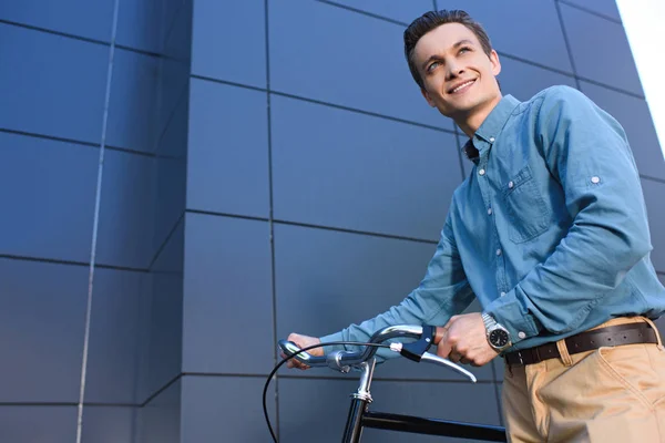 Низький Кут Зору Усміхнений Молодий Чоловік Стоїть Велосипедом Дивиться Вгору — Безкоштовне стокове фото