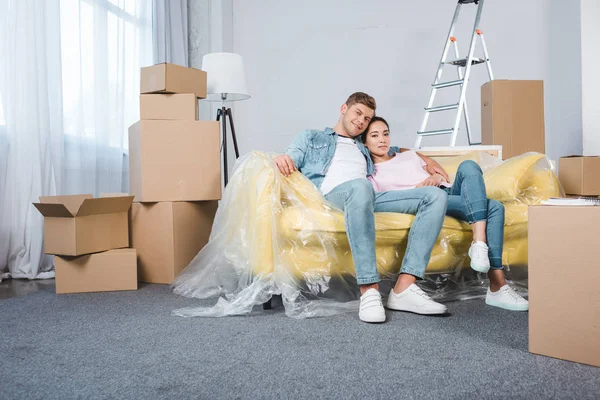 快乐的年轻夫妇在沙发上放松 而搬进新家 — 图库照片
