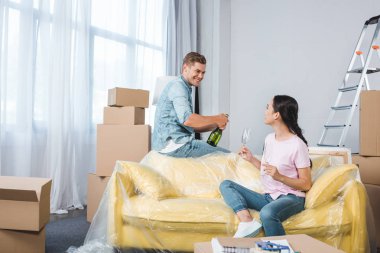 smiling young couple with champagne celebrating after moving into new home clipart