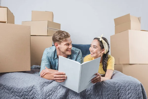Happy Young Couple Photo Album Lying Bed While Moving New — Free Stock Photo