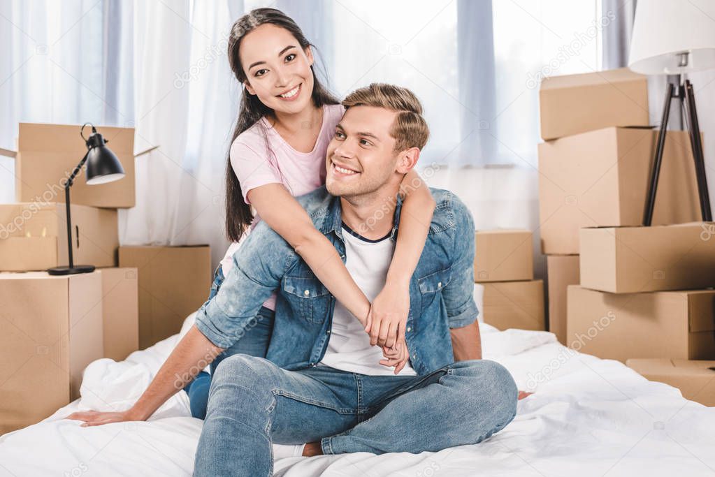 beautiful young couple sitting on bed after moving into new home