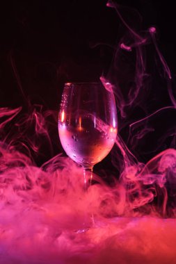 siyah arka plan üzerine pembe dumanlı swirls ile boş bardak