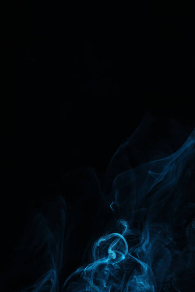 Blue swirl of smoke on black background with copy space