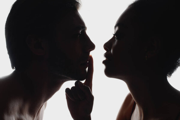 side view of silhouette of african american woman showing silence sign to boyfriend