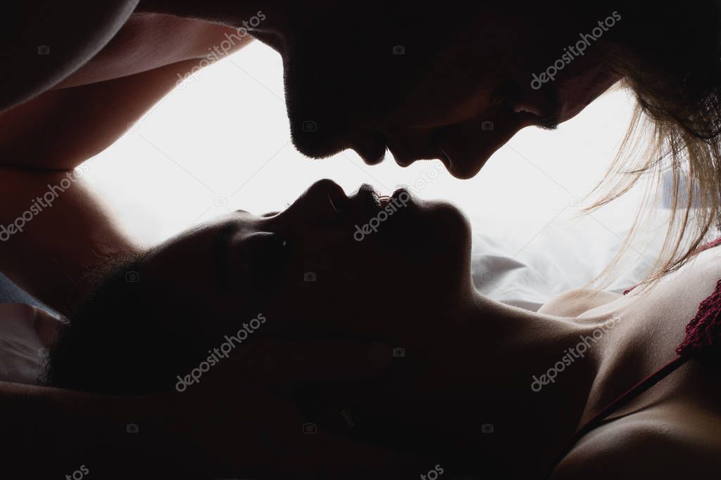 side view of silhouettes of interracial couple in love looking at each other