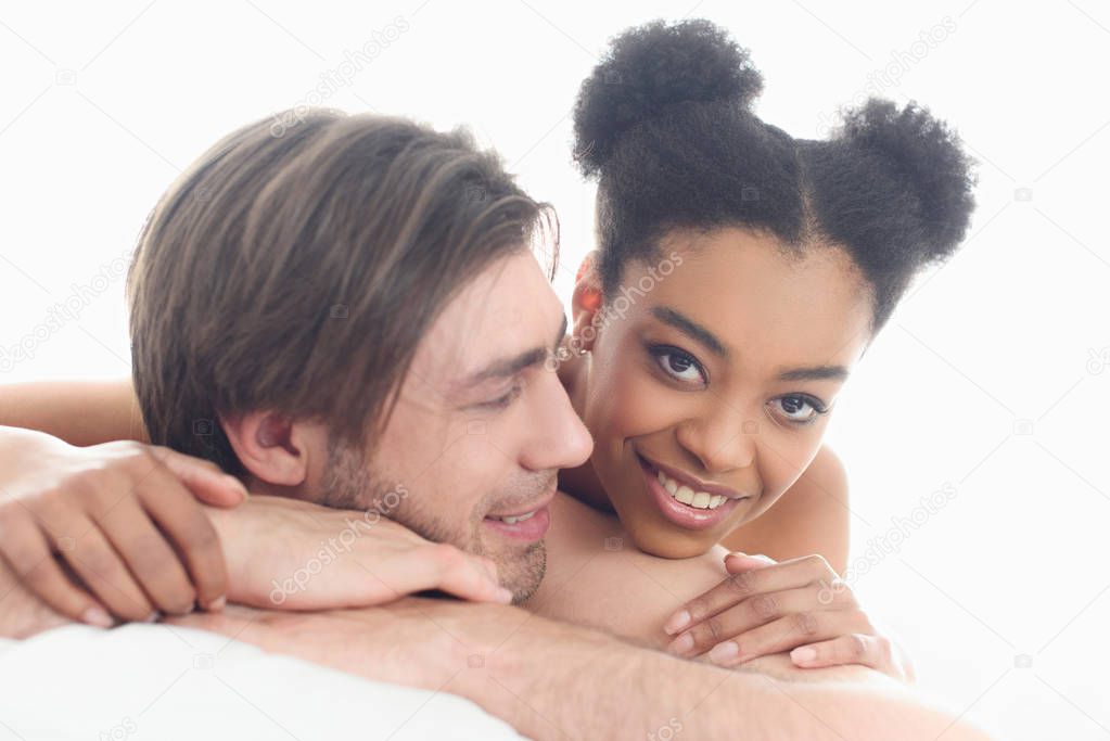 portrait of young interracial couple resting in bed together in morning at home
