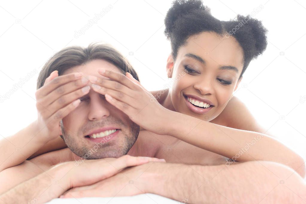 portrait of happy young interracial couple lying in bed in morning at home