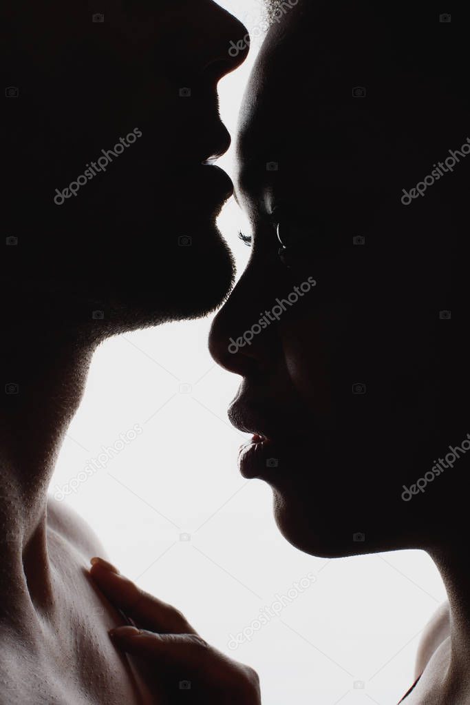 side view of silhouettes of interracial couple in love