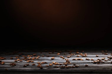 rustic wooden table spilled with coffee beans on black clipart