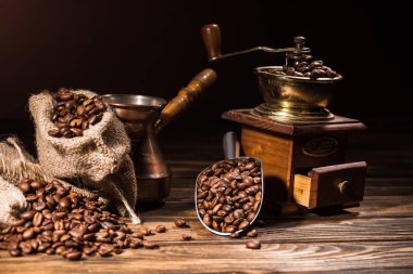 metal scoop, vintage cezve and coffee grinder on rustic wooden table spilled with roasted beans clipart