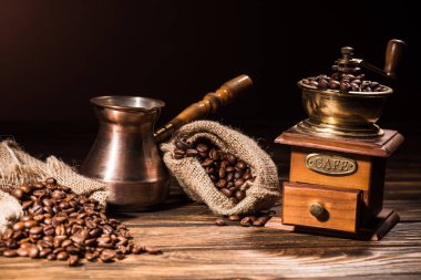 vintage cezve and coffee grinder on rustic wooden table spilled with roasted beans clipart