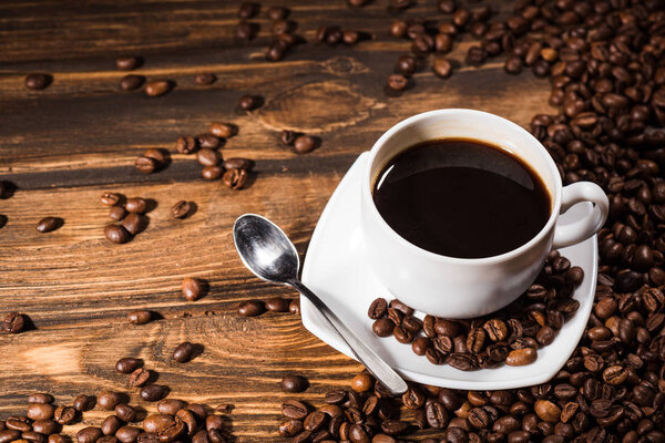 high angle view of coffee cup on rustic wooden table spilled with beans