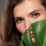 Hermosa chica elegante con hoja de monstera, aislado en gris