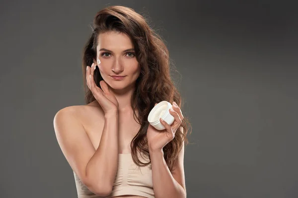 Beautiful Brunette Woman Applying Moisturizing Cream Face Isolated Grey — Stock Photo, Image