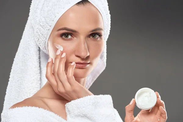 Menina Bonita Roupão Banho Branco Toalha Aplicando Creme Cosmético Rosto — Fotografia de Stock