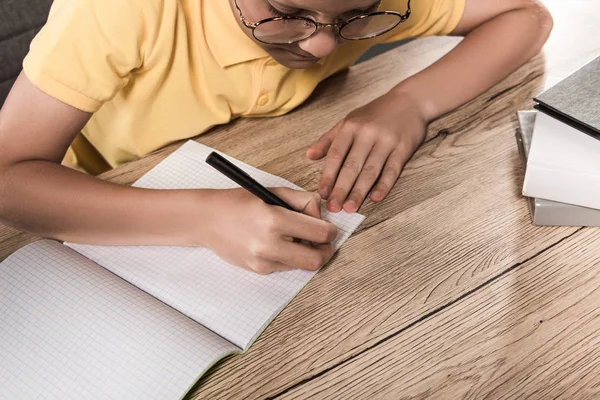 Partial View Schoolboy Eyeglasses Writing Empty Textbook Table Stack Books — Stock Photo, Image