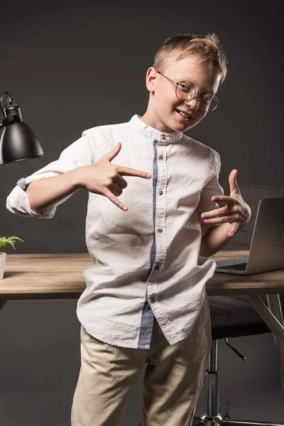 Smiling Little Boy Eyeglasses Gesturing Hands Table Lamp Plant Laptop — Free Stock Photo