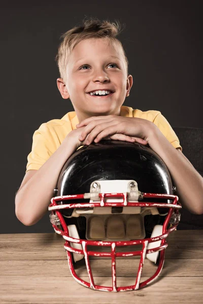 Dromerige Gelukkig Jongetje Zitten Met Amerikaans Voetbal Helm Aan Tafel — Gratis stockfoto