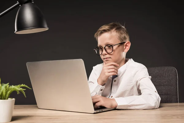 Menino Grave Óculos Usando Laptop Mesa Com Planta Lâmpada Fundo — Fotografia de Stock