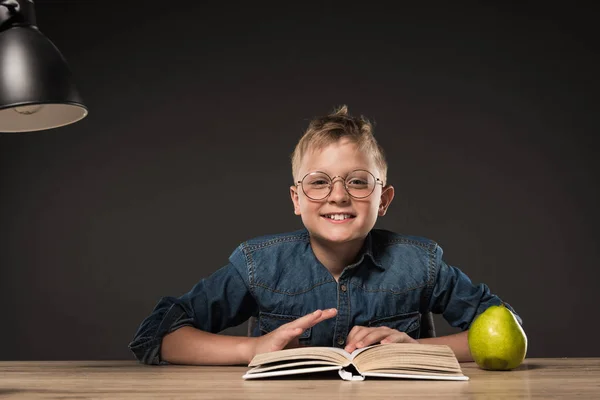 Счастливый Школьник Читающий Книжку Столом Сером Фоне — стоковое фото