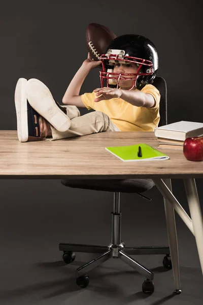 Smiling Schoolboy American Football Helmet Holding Ball Sitting Legs Table — Free Stock Photo