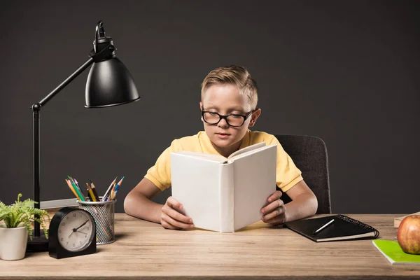 灰色の背景の本 ランプ 色の鉛筆 アップル 時計と教科書とのテーブルで本を読んで眼鏡集中惨殺 — ストック写真