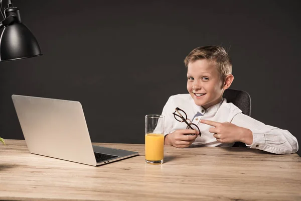 Smiling Little Boy Pointing Finger Eyeglasses Sitting Table Laptop Glass — Free Stock Photo