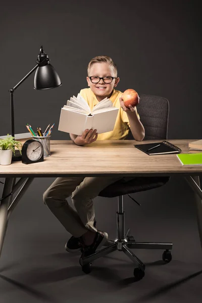 Ler Skolpojke Glasögon Håller Apple Och Läsa Bok Vid Bord — Stockfoto