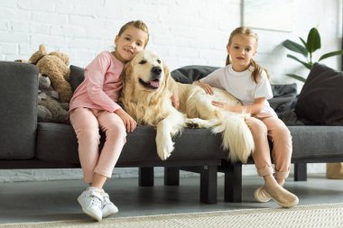 çok güzel çocuklar evde kanepede otururken Golden retriever köpek sarılma