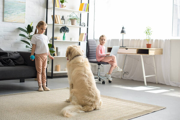 selective focus of little children playing with golden retriever dog at home