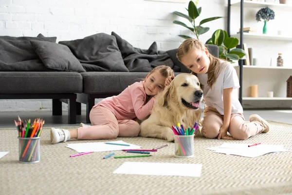 집에서 바닥에 앉아있는 리트리버 강아지를 안고있는 귀여운 — 스톡 사진
