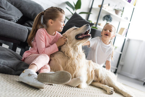 happy adorable kids petting golden retriever dog at home