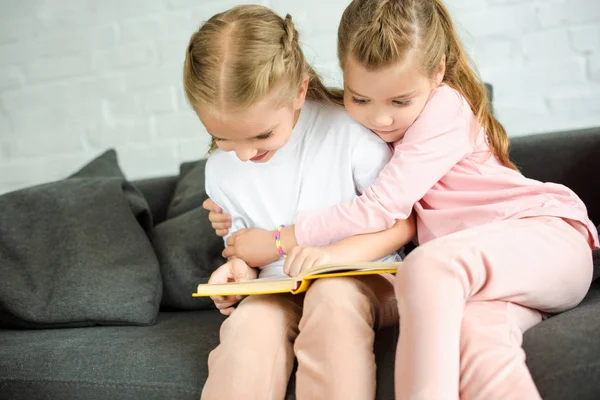 Adorable Little Sisters Reading Book Together Sofa Home — Free Stock Photo