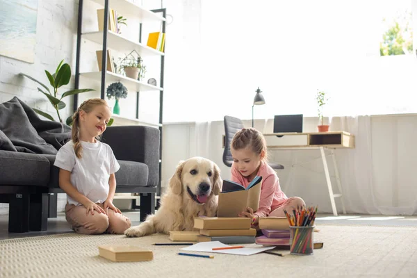 Małe Siostry Czytanie Książek Golden Retriever Pies Pobliżu Przez Domu — Zdjęcie stockowe