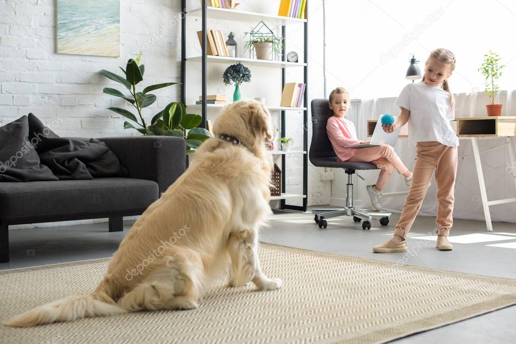 selective focus of little child playing with golden retriever dog at home