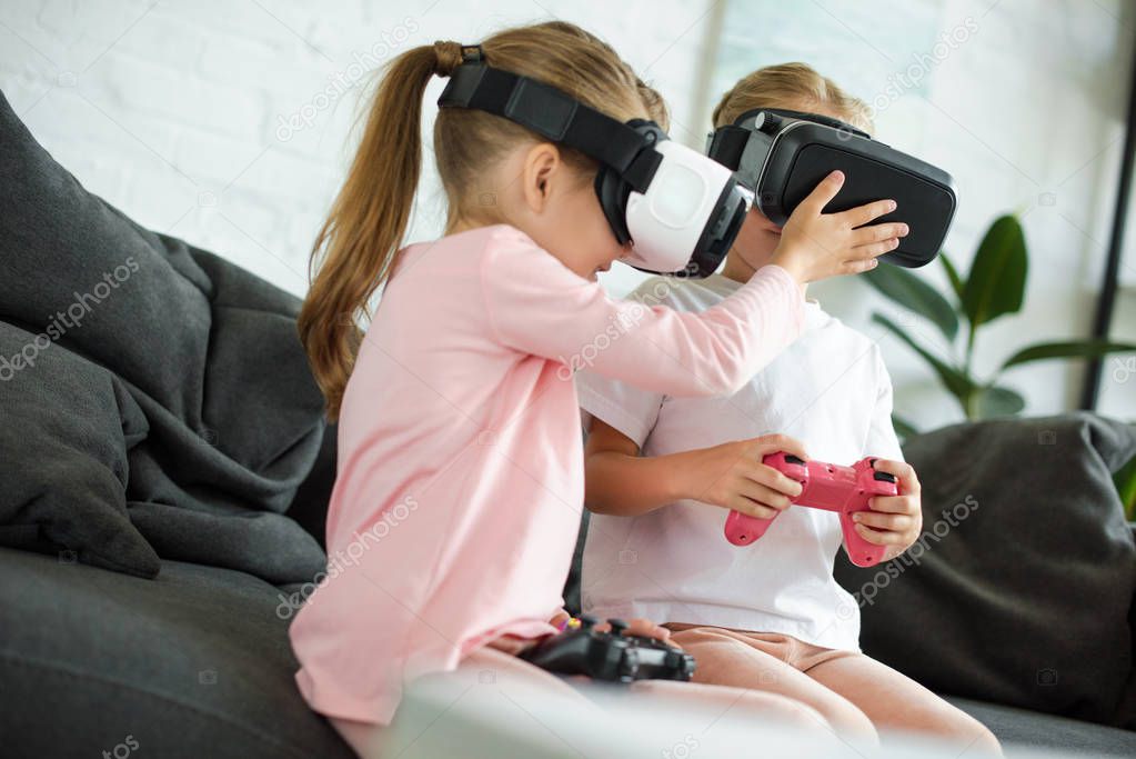 obscured view of kids in virtual reality headsets playing video game on sofa at home