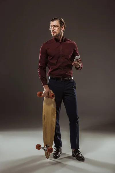 Bel Homme Avec Skateboard Tenant Smartphone Regardant Loin Sur Noir — Photo