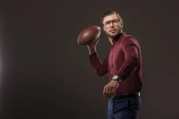 Serious Man Eyeglasses Throwing Rugby Ball Looking Camera Isolated Black — Free Stock Photo