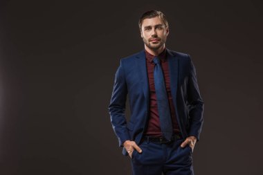 elleri ceplerinde duran ve üzerinde siyah izole kamera bakarak şık elbiseli yakışıklı işadamı