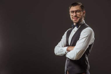 papyon ve çapraz kolları ile duran ve üzerinde siyah izole kamera gülümseyen gözlük yakışıklı şık adam portresi