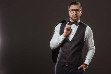papyon ve takım elbise tutan gözlük yakışıklı şık erkek ceket ve siyah izole kamera bakıyor