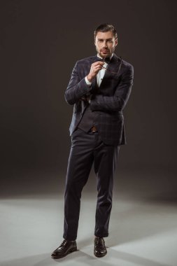 takım elbise ve gözlük tutan ve kameraya seyir siyah papyon yakışıklı adam görünümünü tam uzunlukta