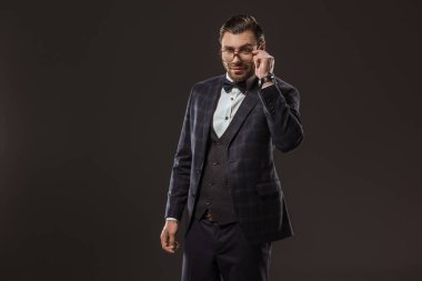 takım elbise ve papyon siyah izole gözlük ayarlama yakışıklı gülümseyen adam portresi