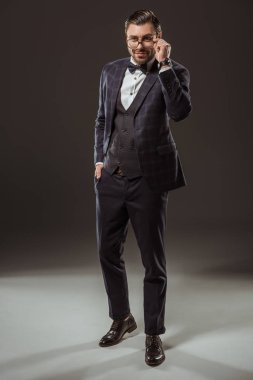 takım elbise ve papyon siyah gözlük ayarlama yakışıklı gülümseyen adam görünümünü tam uzunlukta