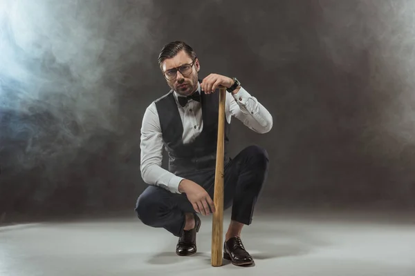 Sérieux Élégant Homme Lunettes Accroupi Avec Batte Baseball Regardant Caméra — Photo